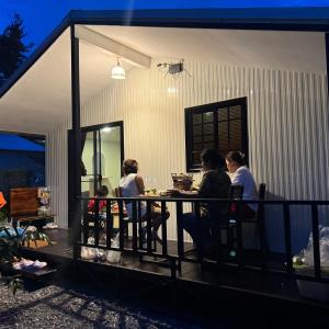 a group of people sitting at a table on a porch at กางเขา แคมป์ปิ้ง in Ban Bung Mai