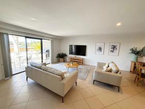 a living room with a couch and chairs and a tv at Jubilee Apartment 06 in South West Rocks