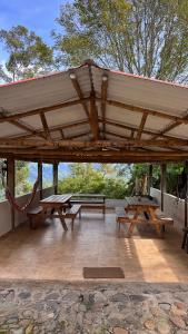 a pavilion with benches and picnic tables on a patio at Eco Finca El Regalo in Salento