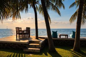 a table and chairs sitting under palm trees on the beach at 1000 Dream Bungalow in Lovina