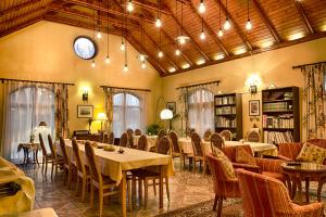 a dining room with tables and chairs and a clock at Ópusztaszeri Erdei Wellness Vendégház in Ópusztaszer