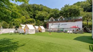 a group of tents in a field with a building at Gapyeong Jmong Choncance&Camping Pension in Gapyeong