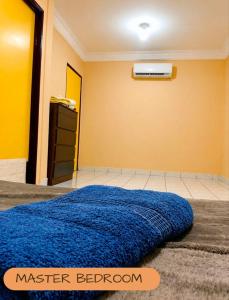 a bedroom with a blue bed and a yellow wall at D'Rembulan Homestay in Ranau