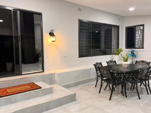 a dining room with a table and chairs and windows at The Hill Manor in Ndola