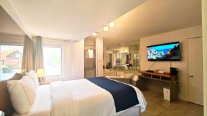 a hotel room with a large bed and a television at Motel des Pentes et Suites in Saint-Sauveur-des-Monts
