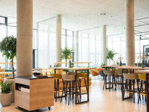 a restaurant with tables and chairs and windows at IBIS STYLES MUENCHEN AIRPORT in Munich