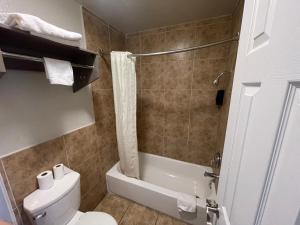 a bathroom with a toilet and a tub and a shower at SimpleStay Suites - Downtown San Bernardino in San Bernardino