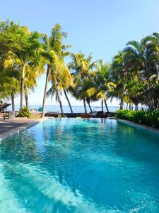 a large swimming pool with palm trees on the beach at 1000 Dream Bungalow in Lovina