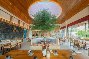 a restaurant with tables and chairs and a tree at Lomo Boutique Hotel & Villas, Uluwatu in Uluwatu