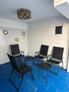 four chairs and tables in a room with blue carpet at L F Suites in Kinshasa