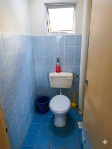 a blue tiled bathroom with a toilet with a window at MonoStay Samarahan in Kota Samarahan