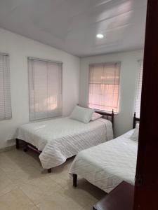 a bedroom with two beds and two windows at Villa Nacha in Villeta