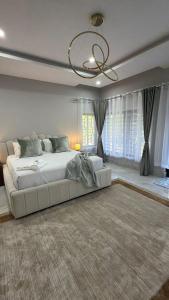 a large white bed in a bedroom with a chandelier at The Hill Manor in Ndola +41 photos
