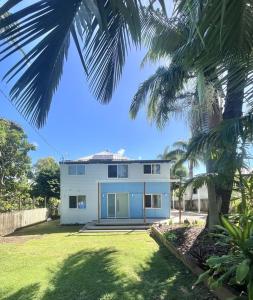 a white house with a palm tree in front of it at Iluka in Yeppoon