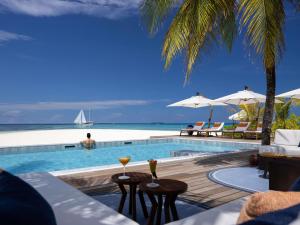 a pool with a view of the ocean and a sailboat at V Villas Maldives at Mirihi - MGallery Collection in Mandhoo