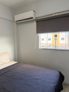 a bedroom with a bed with a blue blanket and a window at Apartamento completo in Nova Mutum
