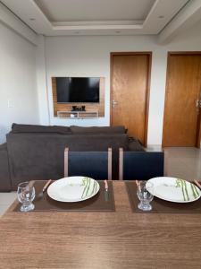 a dining room table with two plates and a couch at Apartamento completo in Nova Mutum