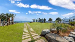 a path leading to a field with the ocean at Stonecove Pension in Geoje