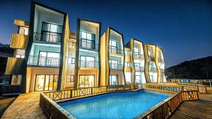 a large building with a swimming pool in front of it at Stonecove Pension in Geoje +6 photos