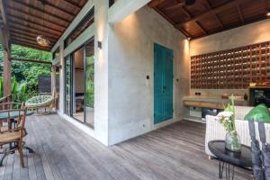 an outdoor patio with a table and chairs and a blue door at Kadewa Retreat Ubud - Adults Only in Ubud