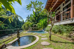 a swimming pool in a garden next to a house at Kadewa Retreat Ubud - Adults Only in Ubud