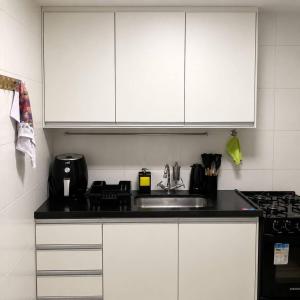 a kitchen with white cabinets and a sink at Apartamento 02 QUARTOS, confortável no coração da Pampulha in Belo Horizonte