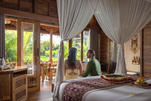 a man and woman standing next to a bed in a room at Edge of Ubud by GenuineHost in Ubud
