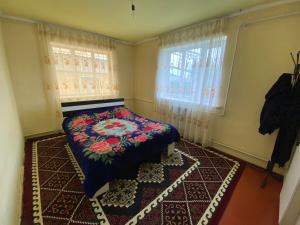 a bedroom with a bed and two windows at ILGIZ HOUSE Barskoon in Barskoon