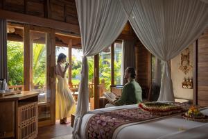 a woman standing next to a bed in a room at Edge of Ubud by GenuineHost in Ubud