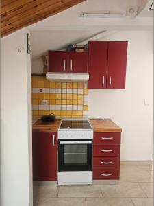 a kitchen with red cabinets and a white stove top oven at Apartmani Banić Apartman 5 in Postira