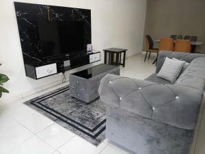 a living room with a couch and a flat screen tv at Nohana Homestay, Alor Gajah in Kampong Jelatang +8 photos