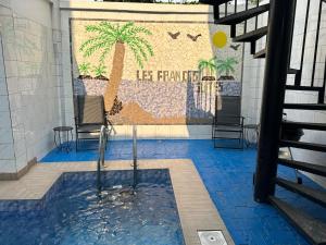 a pool with a palm tree mural on the wall at L F Suites in Kinshasa