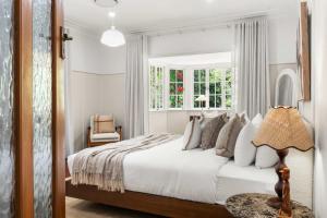 a white bedroom with a bed and a chair at Treehaven House & Cottage - Maleny Retreat in Maleny