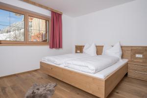 Schlafzimmer mit einem Bett mit weißer Bettwäsche und einem Fenster in der Unterkunft Ferienwohnungen H&P in Alpbach