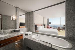 a bathroom with a tub and a bed and a large mirror at InterContinental Hanoi Landmark72 by IHG in Hanoi