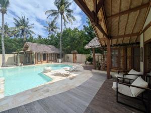 a swimming pool with chairs and a house at Meno Lagoon Bungalows in Gili Meno