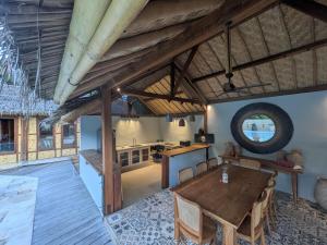 a dining room with a table and a kitchen at Meno Lagoon Bungalows in Gili Meno