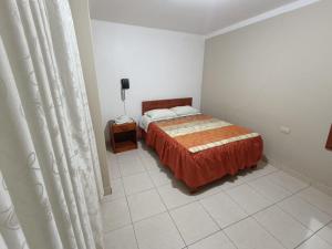a bedroom with a bed with an orange bedspread at Hotel Pradera de los Celajes in Cajamarca