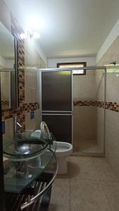 a bathroom with a glass sink and a toilet at Riverwalk cabañas junto al rio in Calarcá +24 photos