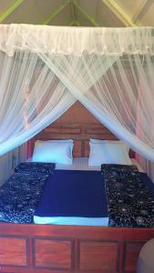 a bedroom with a bed with a mosquito net at Ella Kumi Wood Cabin in Ella +65 photos