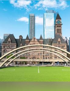 a large building with a bridge over a green field at City Centre Suite, Steps to UofT, TMU, Yonge-Dundas Square in Toronto