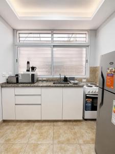 a kitchen with white cabinets and a large window at Paramont Rosario 2 in Rosario de la Frontera