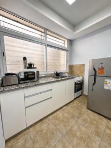 a kitchen with white cabinets and a large window at Paramont Rosario 2 in Rosario de la Frontera +8 photos