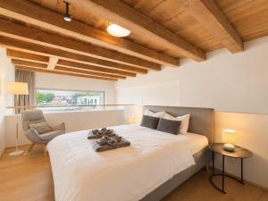 a bedroom with a large white bed and a chair at LAKE-LOFT APARTMENT's direkt im Hafen in Romanshorn