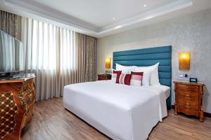 a bedroom with a large white bed and a blue headboard at Windsor Plaza Hotel in Ho Chi Minh City