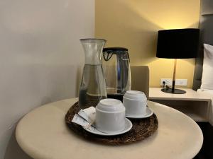a table with two cups and a vase on it at Yes Hotel San Ildefonso Bulacan in Buliran