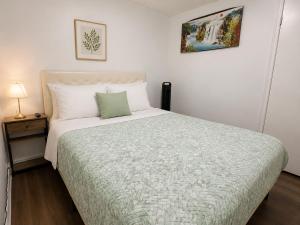 ein Schlafzimmer mit einem Bett mit einer grün-weißen Bettdecke in der Unterkunft TononHouse in Toronto