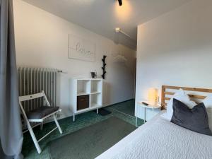 a bedroom with a white bed and a chair at Frühstückspension Irschen in Irschen +57 photos
