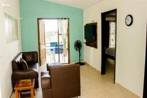 a living room with a couch and a chair and a television at Riverwalk cabañas junto al rio in Calarcá