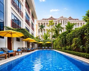 a swimming pool with chairs and umbrellas next to a building at Angkor Mansion & Apartment in Siem Reap